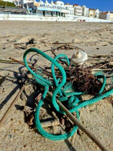 Cordas e fragmentos de lixo marinho presos na praia depois da tempestade.